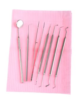 dental surgery instruments on a pink bib (isolated on white background)