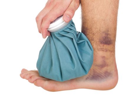 young male icing a sprained ankle with ice pack (isolated on white background)