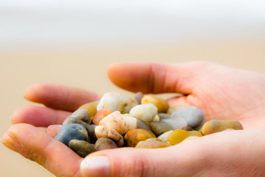 Small colorful stones in hand on sea coast