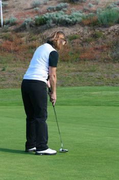 Blond female golfer putting on the green
