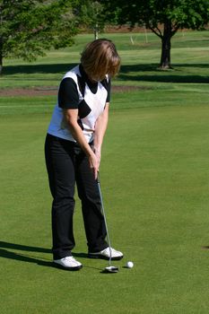 Blond female golfer putting on the green

