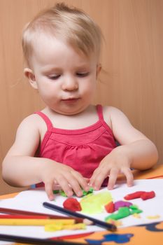 Baby girl moulding from plasticine at table