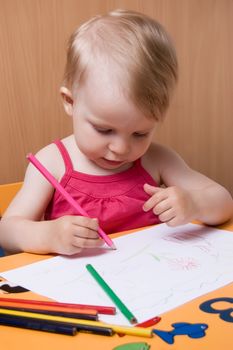 Baby girl coloring with pencils at table