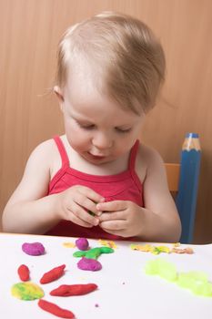 Baby girl moulding from plasticine at table