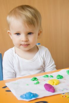 Baby girl moulding from plasticine at table