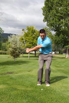 Young golfer playing a chip shot from the rough