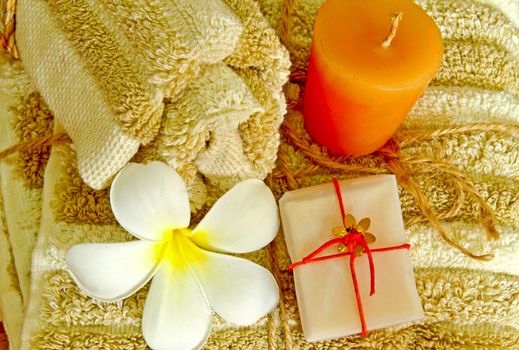 Spa products with flower and candle on towel