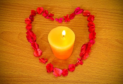 Dry flower heart with candle on wood background