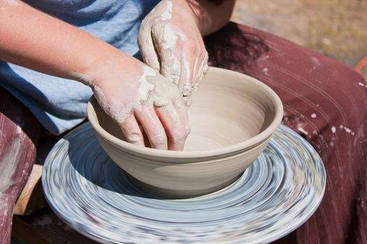 Potter hands working on pottery wheel 