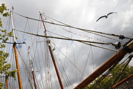 Masts, ropes and flags on sailing ships with rainclouds in background