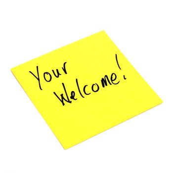 A yellow sticky note is isolated on white with a handwritten note giving welcoming where it is due.