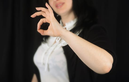 Woman at background indicating ok sign on a black background