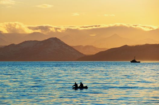 Fishermen by a boat in an evening bay