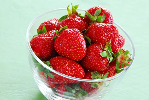 heap of fresh appetizing red strawberries in glass bowl indoors