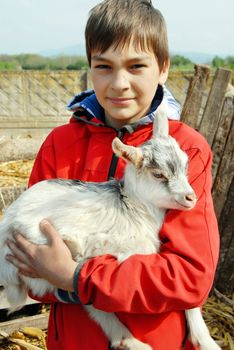 teenage boy portrait outdoors with little goat in hands