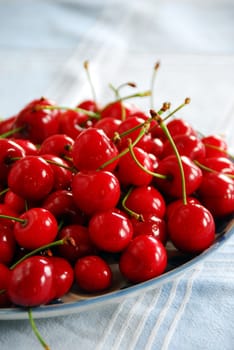 heap of fresh appetizing red cherries on plate indoors