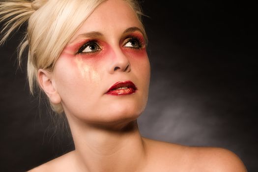 Portrait of a beautiful blond in the studio with extreme red make-up on
