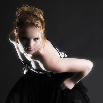 Studio portrait of natural red haired beauty bending towards the camera