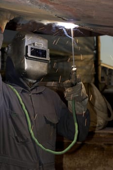 a welder working at shipyard under vessel