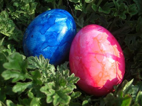 Two brightly-painted Easter eggs in a garden leaning towards each other, symbol of affection and confidence