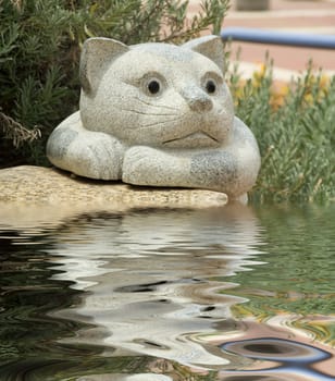 Garden sculpture. Stone cat and its reflection in a reservoir