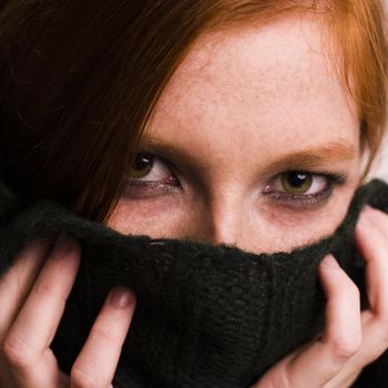 Studio portrait of a natural redhead hiding in her sweater