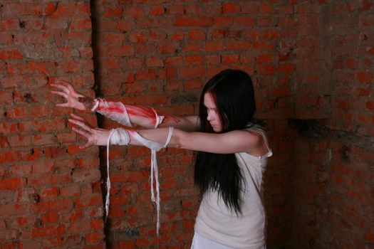 The young girl in a brick cellar with the stained with blood hands