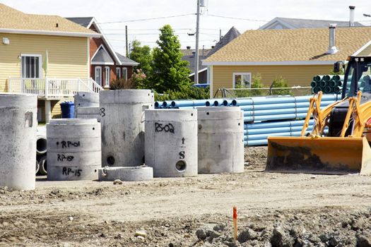 Construction and urban expansion: Stack of concrete sewer and water lines before installation in a new neighborhood of rural North America.