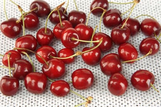 front view of sweet red cherries on white fabric