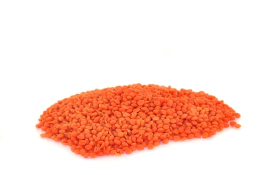 a handful of dried red lentils on a white background
