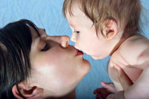 Happy mother kissing the baby holding him in her arms.