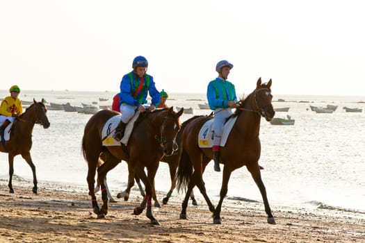 SANLUCAR DE BARRAMEDA, CADIZ, SPAIN - AUGUST 10: Unidentified riders at the start of race horses on Sanlucar de Barrameda beach on August 10, 2011 in Sanlucar de Barrameda, Cadiz, Spain.