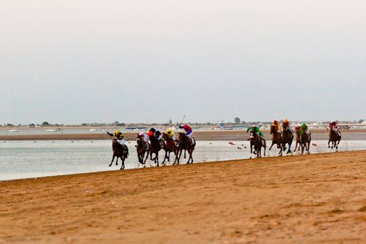 SANLUCAR DE BARRAMEDA, CADIZ, SPAIN - AUGUST 10: Unidentified riders at the start of race horses on Sanlucar de Barrameda beach on August 10, 2011 in Sanlucar de Barrameda, Cadiz, Spain.