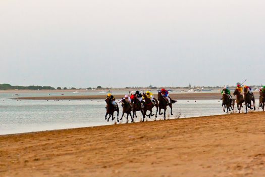 SANLUCAR DE BARRAMEDA, CADIZ, SPAIN - AUGUST 10: Unidentified riders at the start of race horses on Sanlucar de Barrameda beach on August 10, 2011 in Sanlucar de Barrameda, Cadiz, Spain.