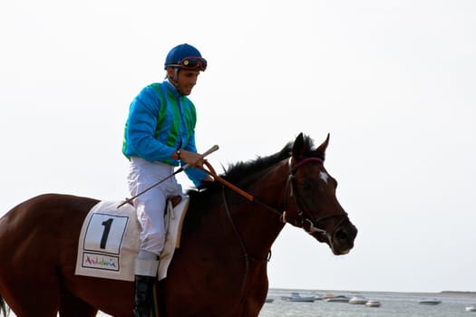 SANLUCAR DE BARRAMEDA, CADIZ, SPAIN - AUGUST 10: Unidentified riders at the start of race horses on Sanlucar de Barrameda beach on August 10, 2011 in Sanlucar de Barrameda, Cadiz, Spain.