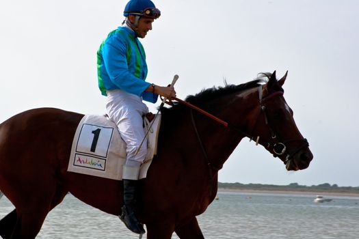 SANLUCAR DE BARRAMEDA, CADIZ, SPAIN - AUGUST 11: Unidentified rider at the start of race horses on Sanlucar de Barrameda beach on August 11, 2011 in Sanlucar de Barrameda, Cadiz, Spain.