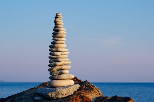 Balancing white pebbles each other on a sea boulder