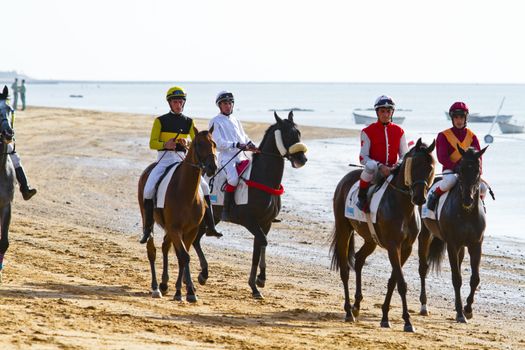 SANLUCAR DE BARRAMEDA, CADIZ, SPAIN - AUGUST 10: Unidentified riders at the start of race horses on Sanlucar de Barrameda beach on August 10, 2011 in Sanlucar de Barrameda, Cadiz, Spain.