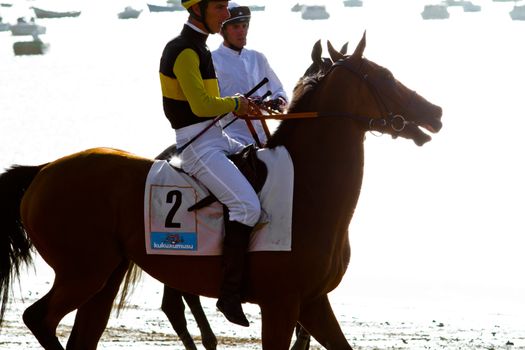 SANLUCAR DE BARRAMEDA, CADIZ, SPAIN - AUGUST 10: Unidentified riders at the start of race horses on Sanlucar de Barrameda beach on August 10, 2011 in Sanlucar de Barrameda, Cadiz, Spain.