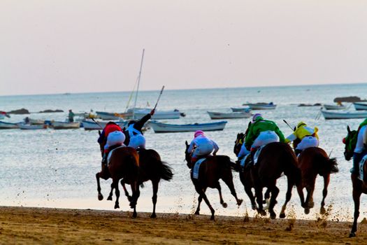 SANLUCAR DE BARRAMEDA, CADIZ, SPAIN - AUGUST 10: Unidentified riders race horses on Sanlucar de Barrameda beach on August 10, 2011 in Sanlucar de Barrameda, Cadiz, Spain.