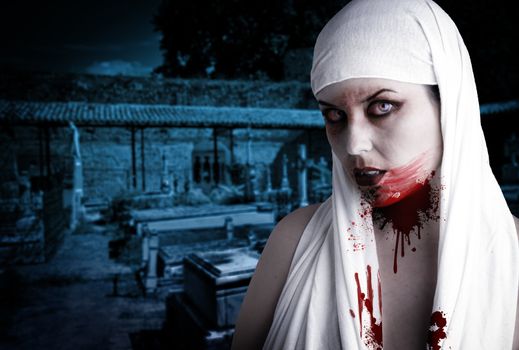 Female vampire with blood stains in a cemetery. Gothic Image halloween