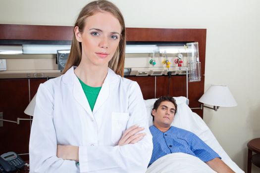 Young female doctor in hospital with patient lying on bed in background