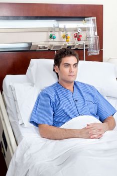 Serious patient sitting on bed in hospital