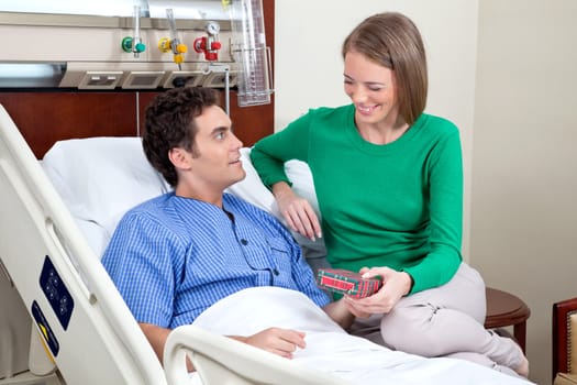 Wife giving present to her husband in hospital