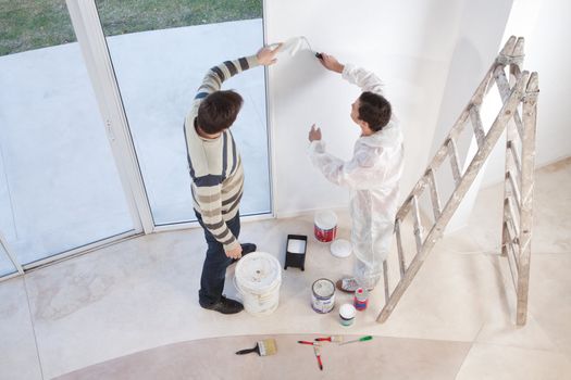 Young man showing a spot on the wall to painter