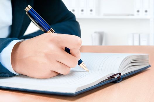 Cropped image of hand of young woman taking notes