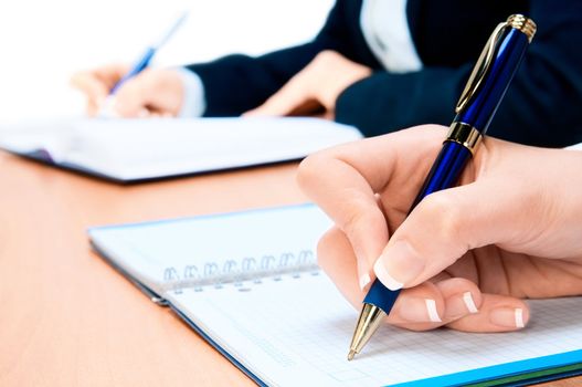 Cropped image of hand of young woman taking notes