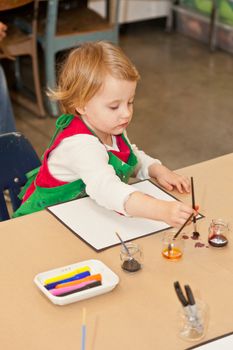 Cute little baby girl having fun painting at art class