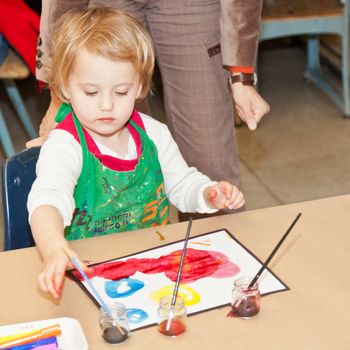 Cute little baby girl having fun painting at art class