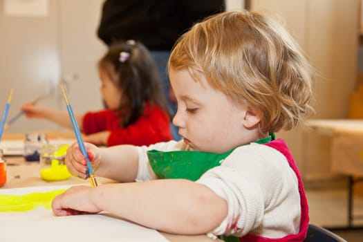 Cute little baby girl having fun painting at art class